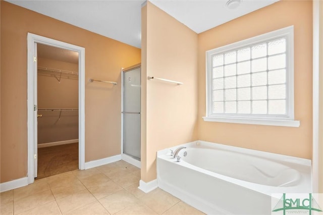 bathroom with a stall shower, a garden tub, a spacious closet, and tile patterned floors