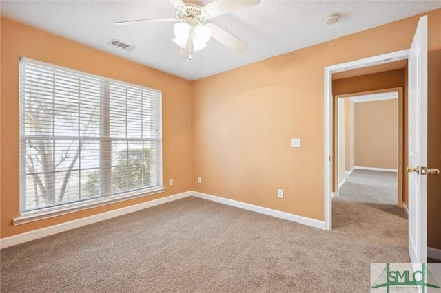 carpeted empty room with visible vents, ceiling fan, and baseboards