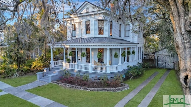 neoclassical / greek revival house featuring an outbuilding, metal roof, a porch, a storage shed, and a front lawn