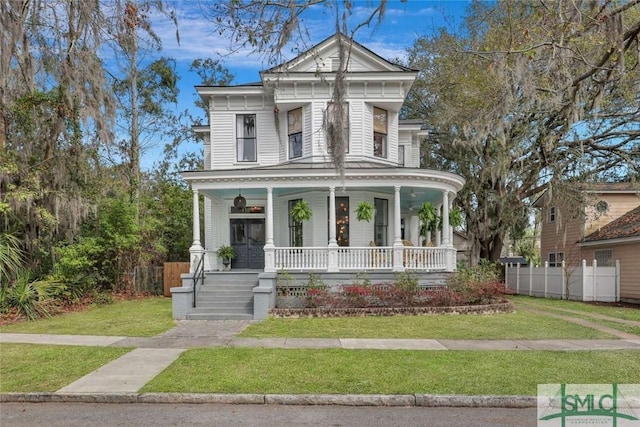 greek revival house with covered porch, fence, and a front lawn