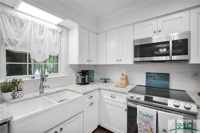 kitchen with ornamental molding, appliances with stainless steel finishes, backsplash, and a sink