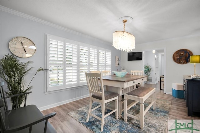 dining space with ornamental molding, light wood-type flooring, a notable chandelier, and baseboards