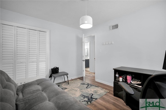 living area featuring visible vents, baseboards, and wood finished floors