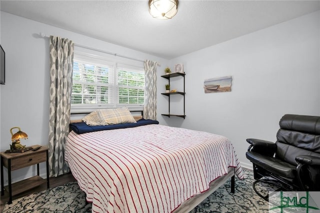 bedroom featuring a textured ceiling, wood finished floors, and baseboards