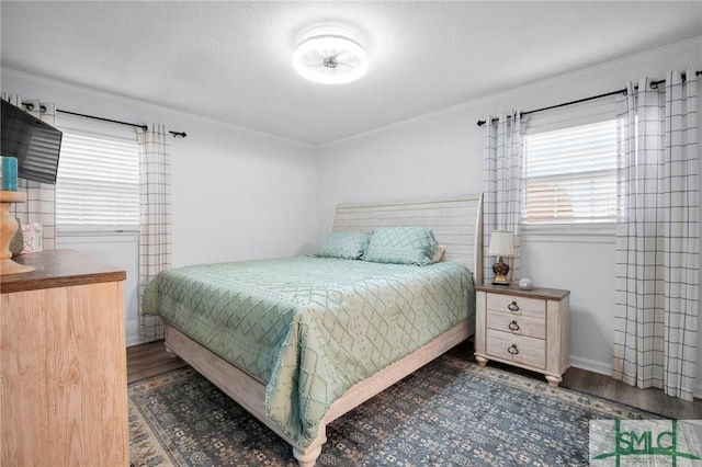 bedroom with crown molding, baseboards, and wood finished floors