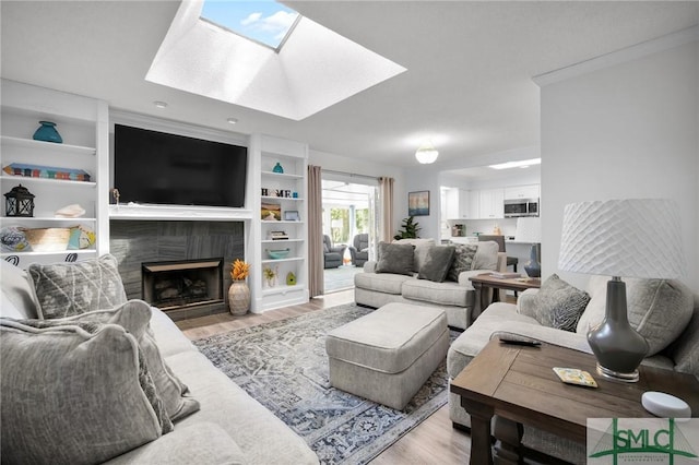 living room featuring wood finished floors, a skylight, and a tile fireplace