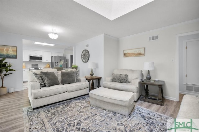 living room with light wood-style floors, visible vents, and crown molding