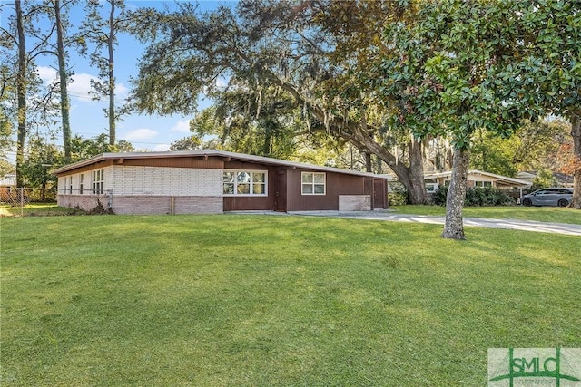 view of front of home featuring fence, a front lawn, concrete driveway, and brick siding