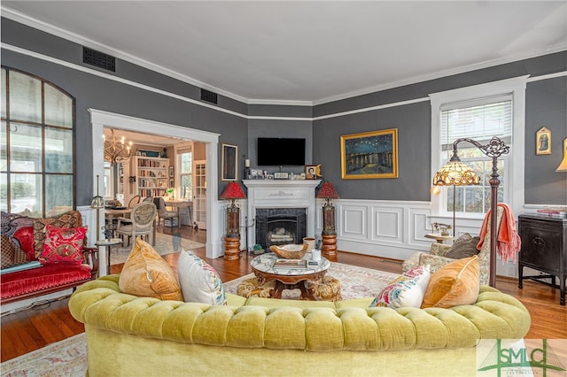 living room featuring a chandelier, ornamental molding, a premium fireplace, and wood finished floors