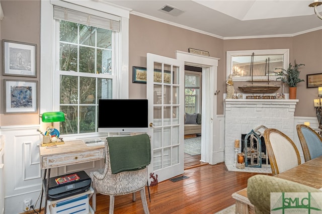 office area featuring a fireplace, visible vents, hardwood / wood-style floors, and ornamental molding