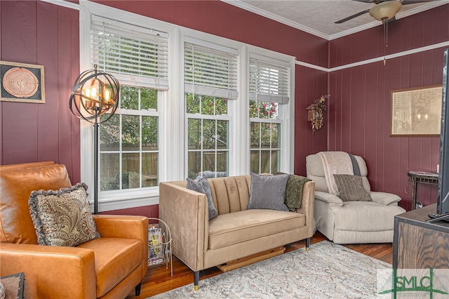 sitting room with a textured ceiling, ceiling fan with notable chandelier, wood finished floors, and crown molding