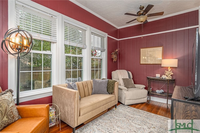 sitting room with a textured ceiling, ornamental molding, ceiling fan with notable chandelier, and wood finished floors