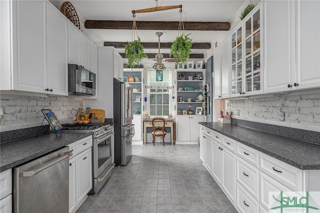 kitchen featuring stainless steel appliances, glass insert cabinets, dark countertops, and white cabinetry