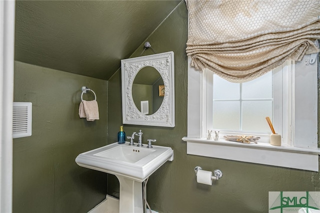 bathroom with lofted ceiling, visible vents, and a textured ceiling