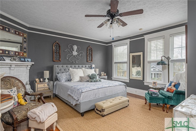 bedroom with a brick fireplace, a ceiling fan, ornamental molding, and wood finished floors