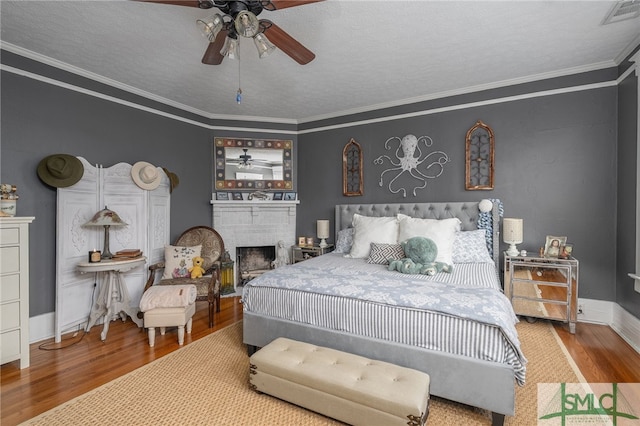 bedroom with crown molding, a fireplace, visible vents, and wood finished floors