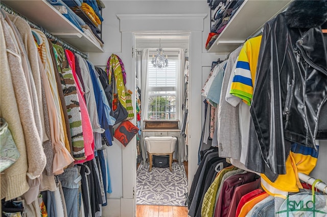 walk in closet featuring wood finished floors and a notable chandelier