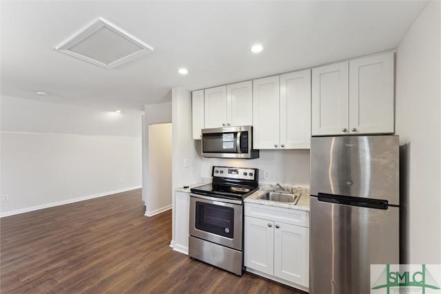 kitchen featuring stainless steel appliances, white cabinetry, dark wood finished floors, and baseboards