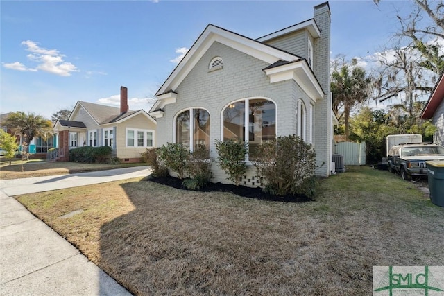 view of front of property featuring a front yard, brick siding, and a chimney