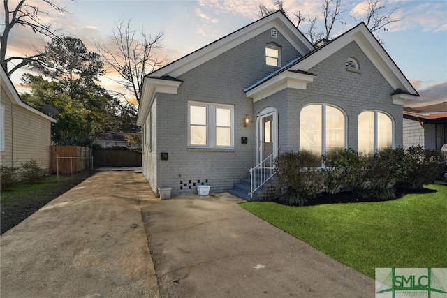 view of front of property with brick siding, a lawn, and fence