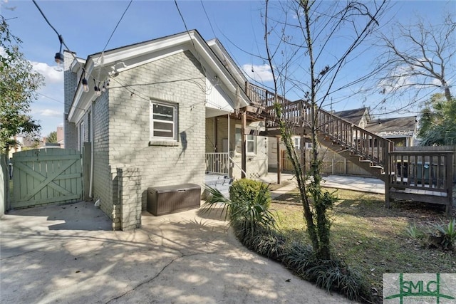 view of home's exterior featuring a gate, brick siding, a patio, and a chimney