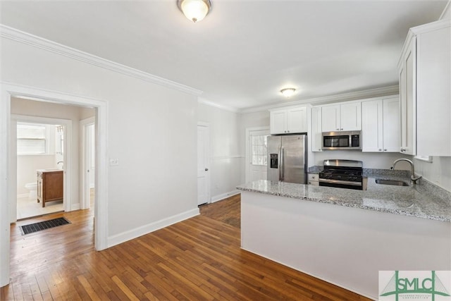 kitchen with dark wood-style flooring, light stone countertops, stainless steel appliances, crown molding, and a sink