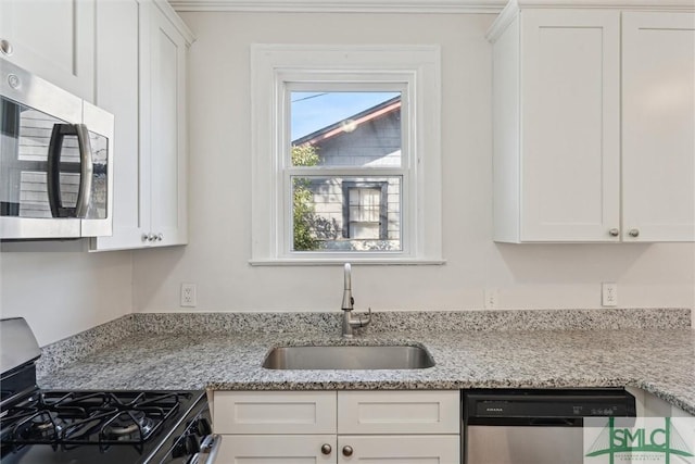 kitchen with stainless steel appliances, white cabinets, a sink, and light stone counters