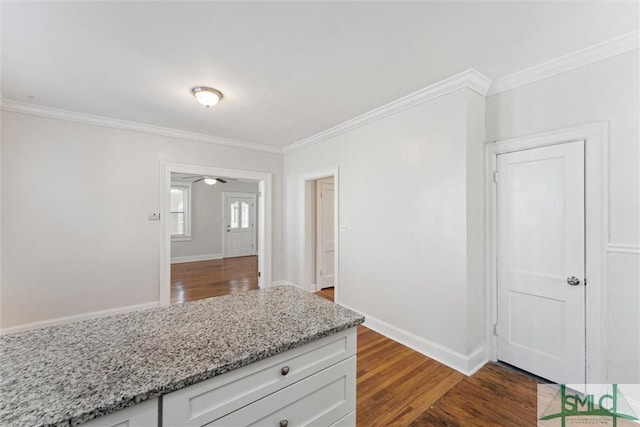 kitchen with light stone counters, wood finished floors, baseboards, white cabinets, and crown molding