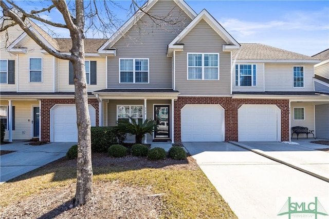 townhome / multi-family property with driveway, an attached garage, and brick siding