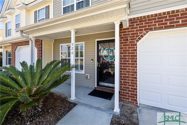 entrance to property featuring a garage and brick siding