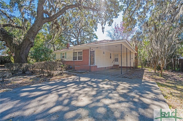 view of front facade featuring aphalt driveway, an attached carport, crawl space, fence, and brick siding