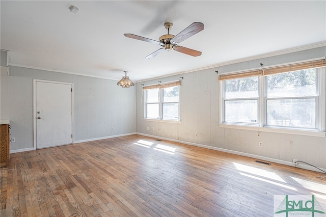 empty room featuring visible vents, baseboards, hardwood / wood-style flooring, ceiling fan, and ornamental molding