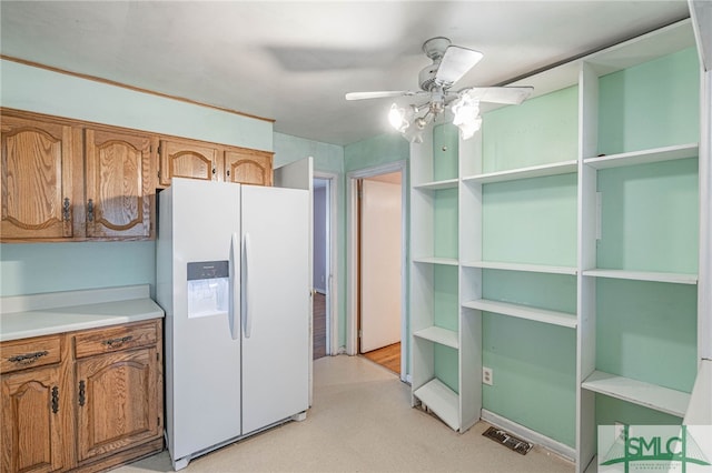 kitchen featuring ceiling fan, white refrigerator with ice dispenser, light countertops, brown cabinets, and open shelves