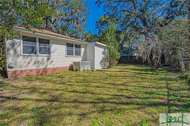 view of side of home with a yard, cooling unit, and fence