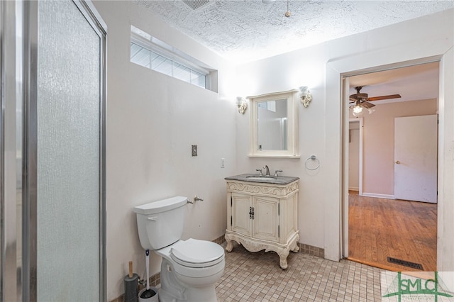 bathroom with a ceiling fan, toilet, tile patterned flooring, a textured ceiling, and vanity