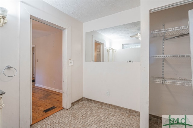 bathroom with a textured ceiling, tile patterned flooring, visible vents, and baseboards