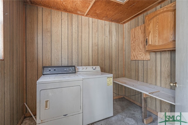 laundry room with laundry area, wood walls, and washer and clothes dryer