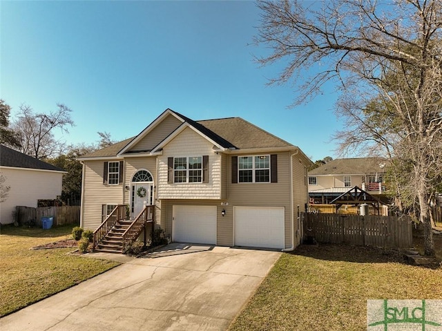 split foyer home featuring a garage, concrete driveway, a front yard, and fence