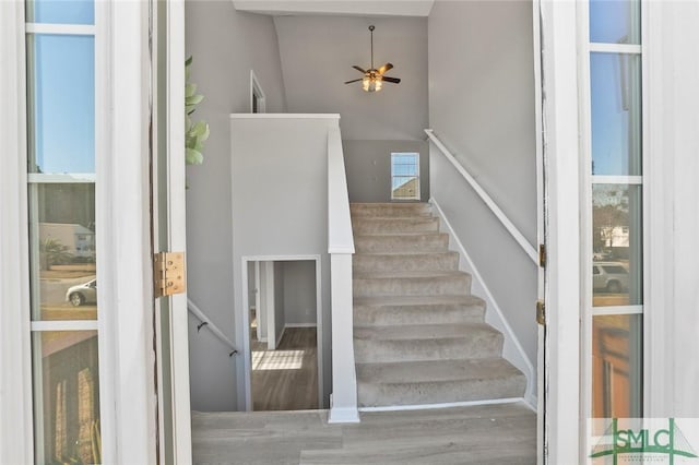 stairway with ceiling fan and a high ceiling