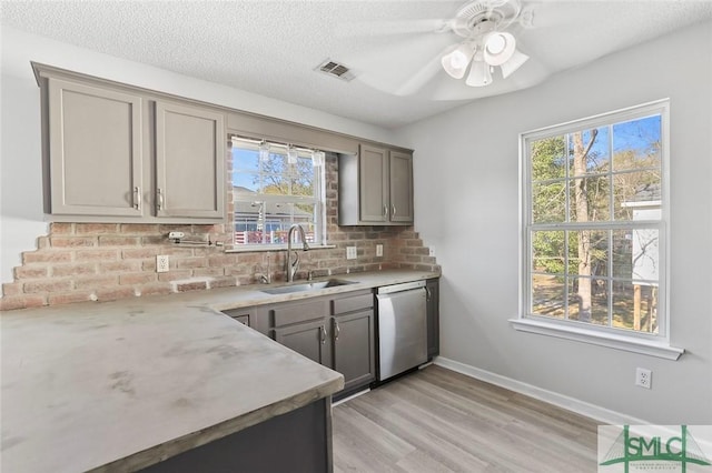 kitchen featuring gray cabinetry, a sink, light countertops, light wood-type flooring, and dishwasher