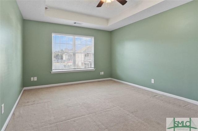 spare room with carpet floors, baseboards, a raised ceiling, and a ceiling fan