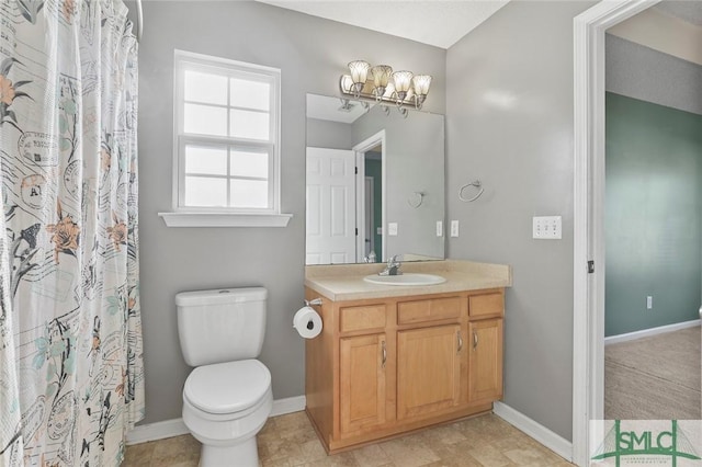 bathroom with baseboards, vanity, toilet, and an inviting chandelier