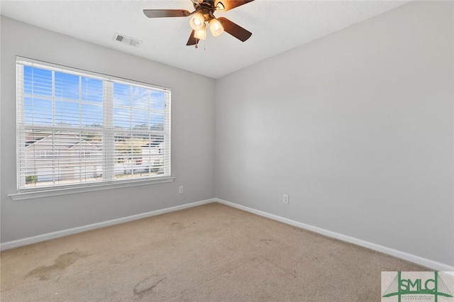 carpeted spare room with a ceiling fan, visible vents, and baseboards