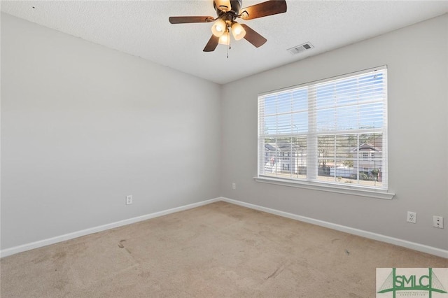 spare room with a textured ceiling, carpet floors, visible vents, and baseboards