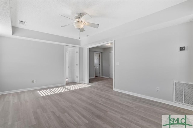 spare room with ceiling fan, wood finished floors, visible vents, and baseboards