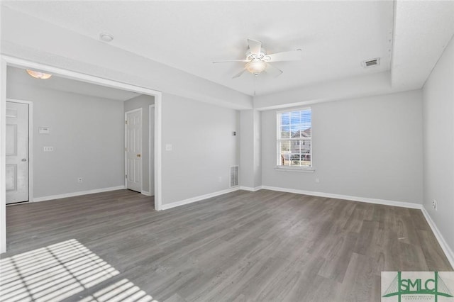 empty room featuring baseboards, visible vents, ceiling fan, and wood finished floors