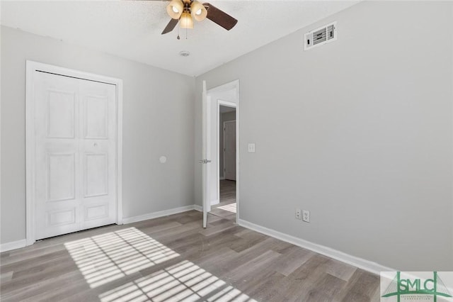 unfurnished bedroom featuring baseboards, visible vents, and wood finished floors