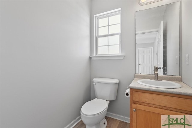 bathroom with wood finished floors, vanity, toilet, and baseboards