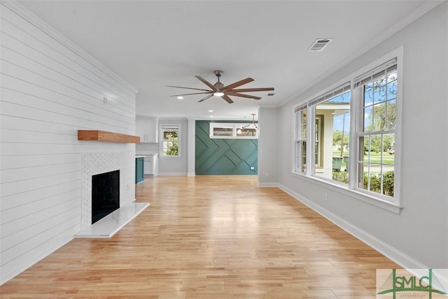 unfurnished living room featuring a large fireplace, visible vents, baseboards, a ceiling fan, and light wood-style floors