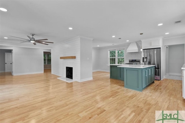 kitchen featuring a fireplace, stainless steel appliances, light countertops, custom range hood, and visible vents